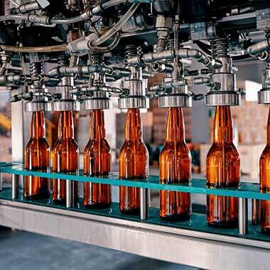 Steklenice se pomikajo skozi obrat za proizvodnjo pijač. Spremljanje raztopljenega kisika je pomembno za upravljanje kakovosti izdelkov.